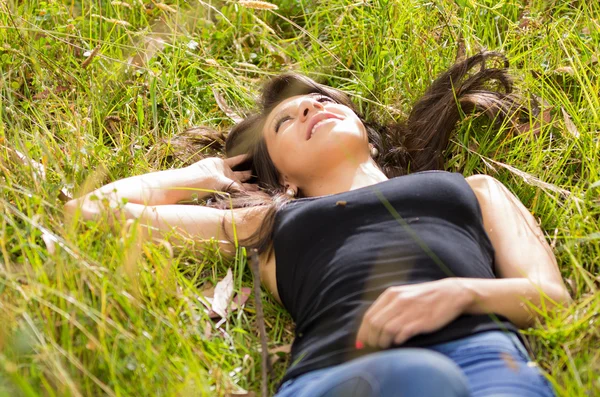 Mooie brunette jonge meisje rustend op groene gras — Stockfoto