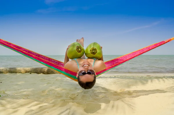 Beautiful young girl lying in a hammock holding two coconuts — Stock Photo, Image