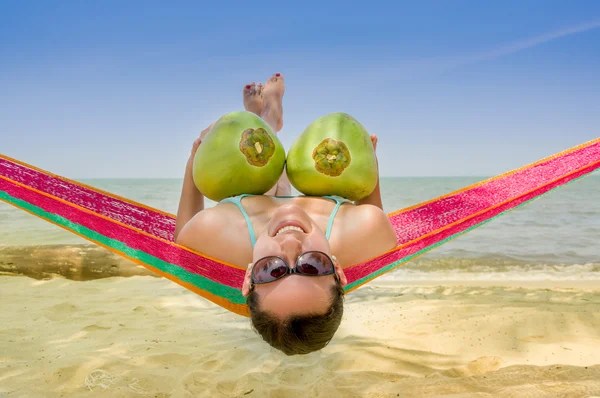 Young girl lying in a hammock holding two coconuts — Stock Photo, Image