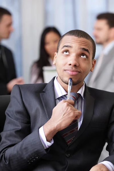 Pensive african-american business man with his coworkers on the background — Stock Photo, Image