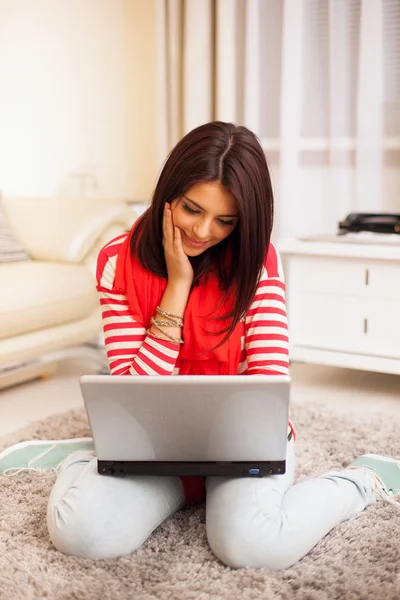 Portret van een jonge vrouw thuis zitten met laptop op de flo — Stockfoto