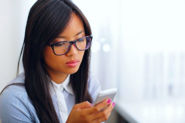 genç güzel Asyalı işkadını onun smartphone kullanarak