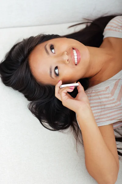 Felice donna asiatica sdraiata sul divano mentre parla al telefono — Foto Stock