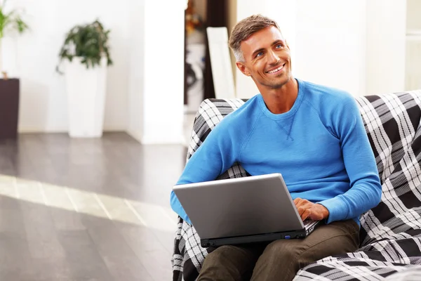 Hombre joven guapo usando el ordenador portátil en casa — Foto de Stock