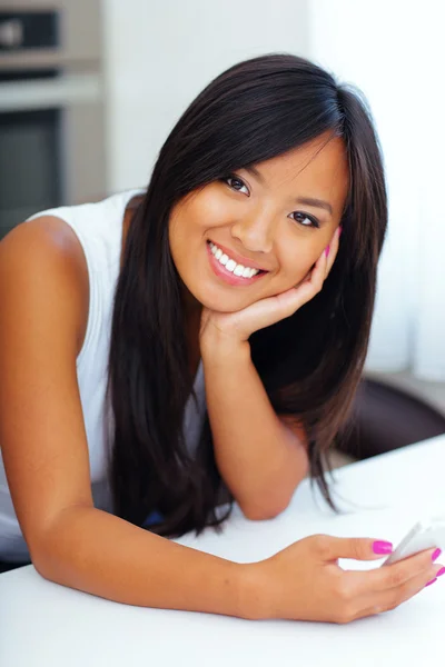 年轻的幸福亚洲女人在家里她智能手机 — 图库照片