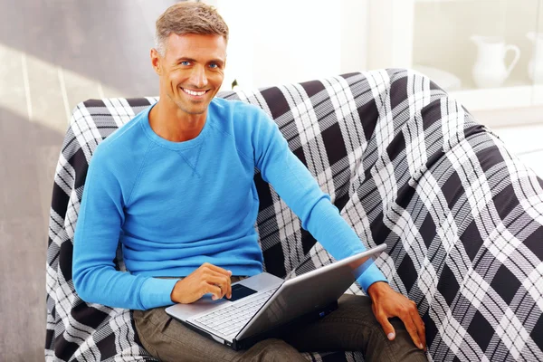 Przystojny młody człowiek korzystający z laptopa w domu — Zdjęcie stockowe
