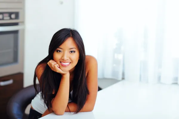 Happy beautiful asian woman leaning on hand in her kitchen — Stock Photo, Image