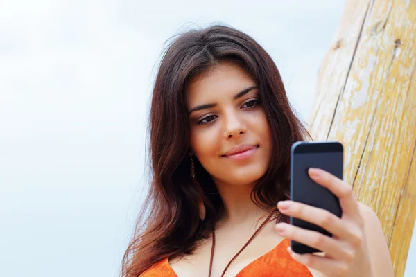Boldog fiatal nő használ a smartphone a strandon — Stock Fotó
