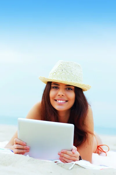 Beautiful woman in swimming suit using her tablet on the beach — Stock Photo, Image