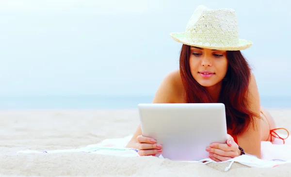 Mooie vrouw in zwemmen pak met behulp van haar Tablet PC op het strand — Stockfoto