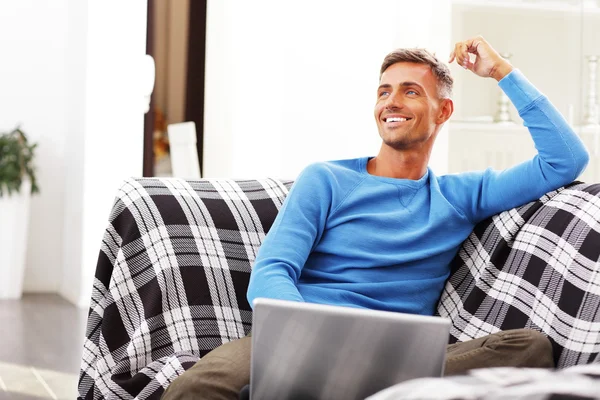 Jovem bonito usando laptop em casa — Fotografia de Stock