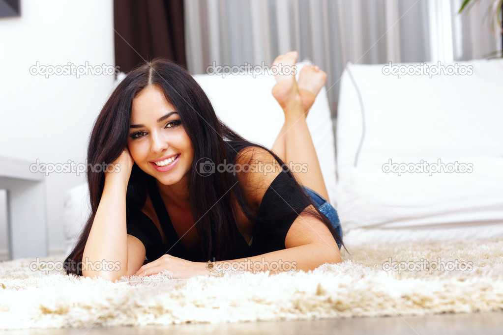 Smiling woman posing while lying on a carpet in the living room
