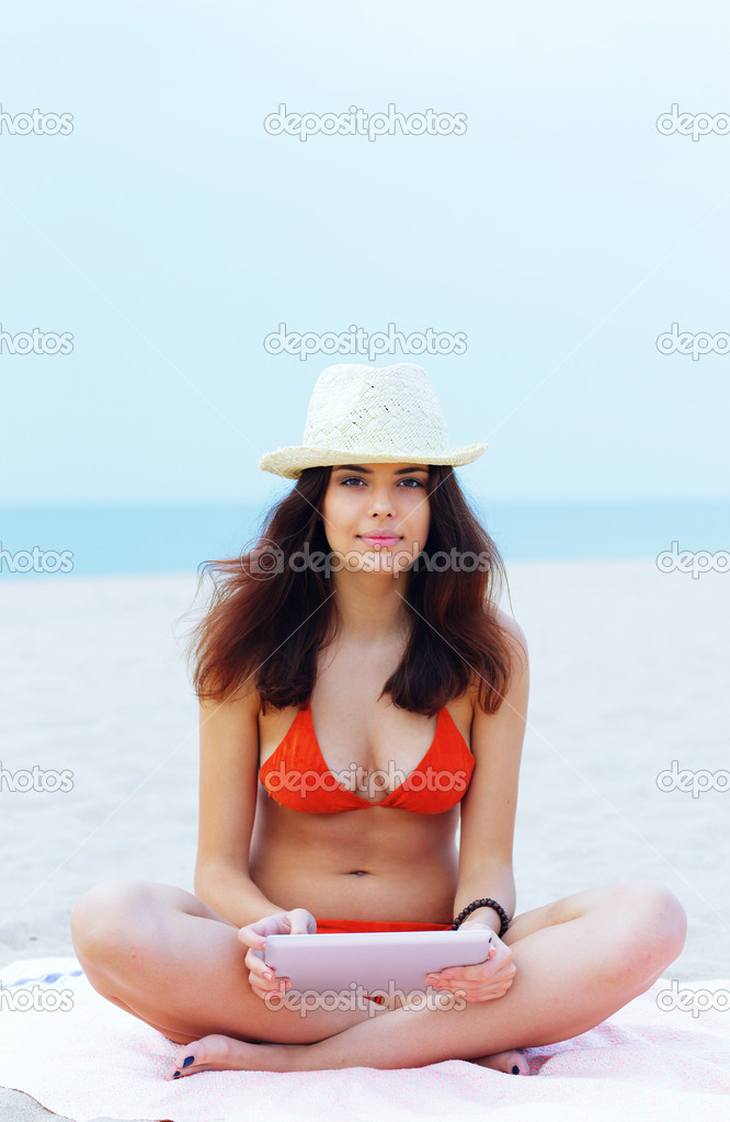 Woman in swimming suit using her tablet on the beach