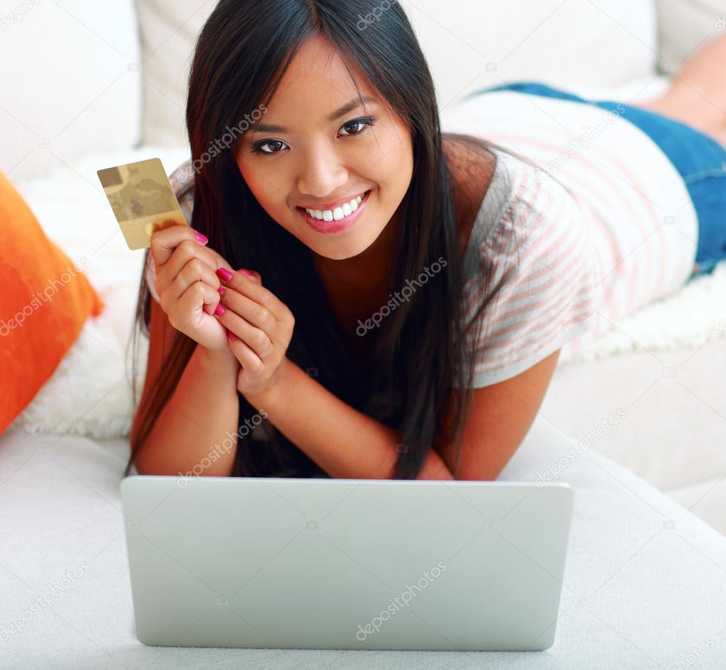Asian woman shopping on-line at home with her credit card