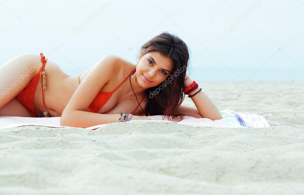 Beautiful woman in bright swimming suit lying on the beach