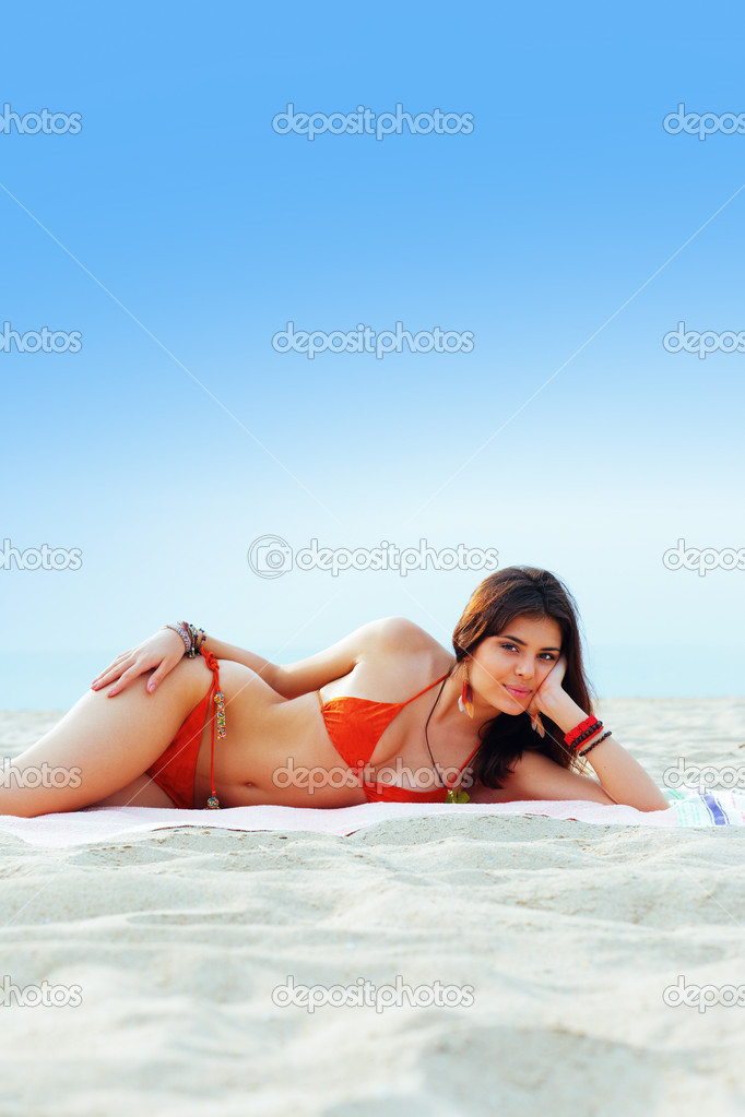 Beautiful woman in bright swimming suit lying on the beach
