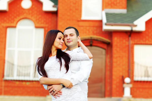 Pareja feliz de pie frente a un nuevo hogar — Foto de Stock