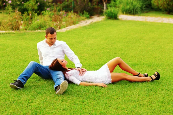 Pareja joven descansando y el césped en el parque — Foto de Stock