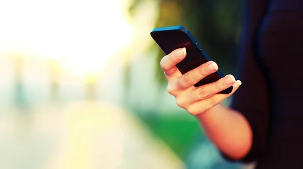 Mano femenina usando un teléfono inteligente — Foto de Stock