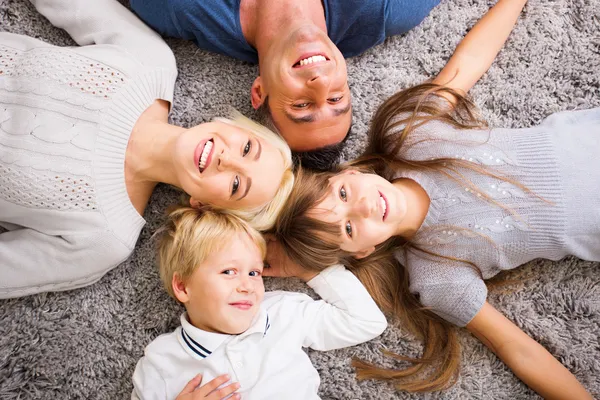 Família deitada no tapete e olhando para cima — Fotografia de Stock