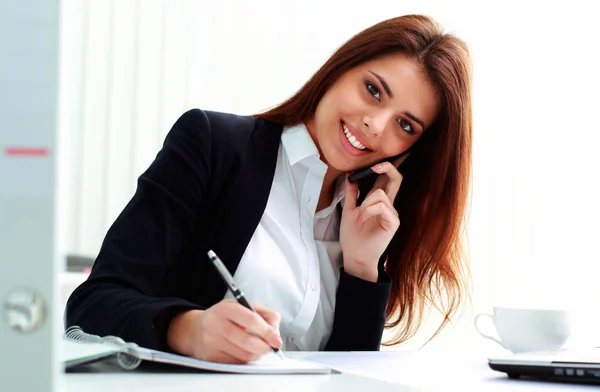 Affärskvinna prata i telefon och skriva noter — Stockfoto