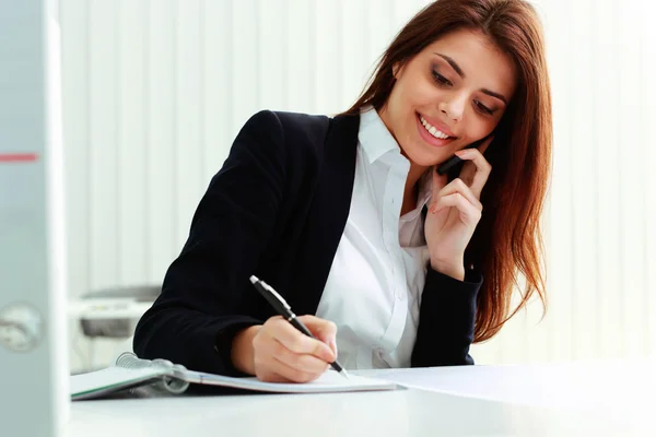 Empresária falando ao telefone e escrevendo notas — Fotografia de Stock