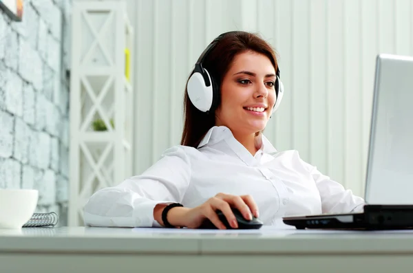 Mujer de negocios en auriculares que trabajan en una computadora portátil — Foto de Stock