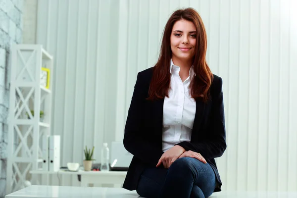 Businesswoman sitting on the table in office — Stock Photo, Image