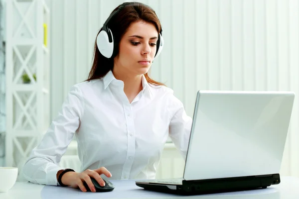 Zakenvrouw in hoofdtelefoon werken op een laptop — Stockfoto