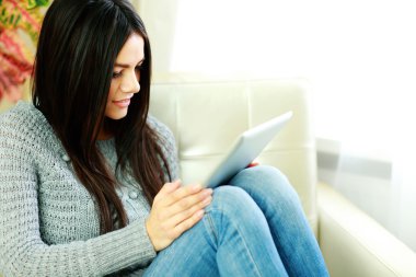 tablet bilgisayar ile koltuk üzerinde oturan kadın