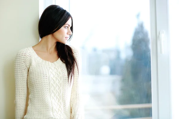 Unga vackra kvinnan tittar på fönster — Stockfoto
