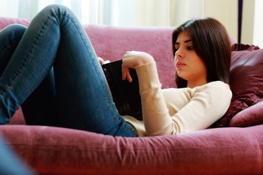 kadın kanepede yatan ve kitap okuma