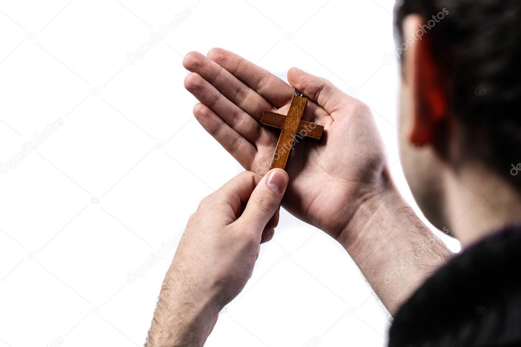 Male hands holding wooden cross