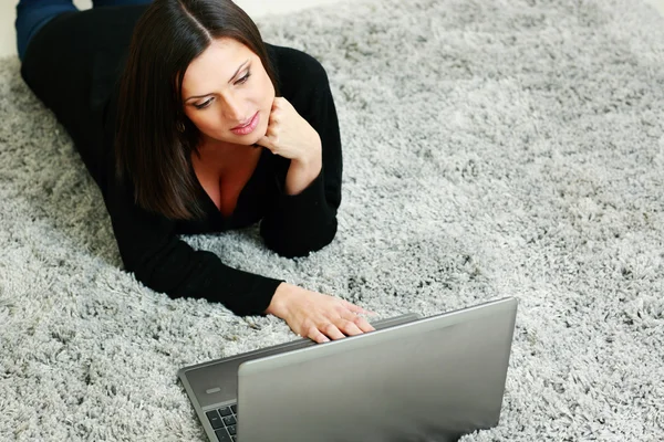 Mujer acostada en la alfombra y utilizando el ordenador portátil —  Fotos de Stock