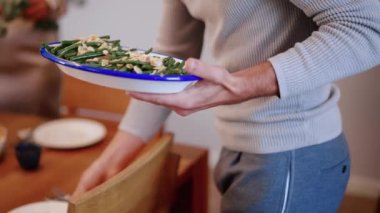 Şükran Günü için geleneksel tabak ve çiçeklerle tatil masasını süsleyen insanların kırpılmış görüntüsü.
