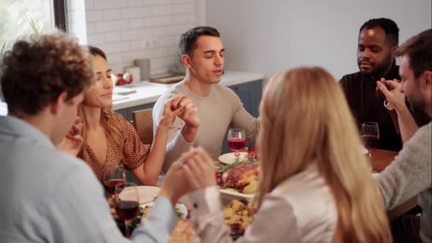 感謝祭の日を祝う前に一緒に食事をする前にテーブルの周りに手を握る友人 — ストック動画