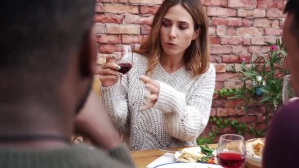 家の近くのテラスに座っている彼女の友人と一緒に夕食を祝いながら話している美しい女性 — ストック動画