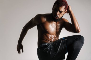 Siyah tişörtsüz sporcu beyaz arka planda tek başına çalışırken egzersiz yapıyor.