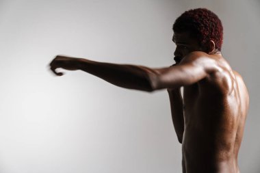 Siyah tişörtsüz sporcu beyaz arka planda tek başına çalışırken egzersiz yapıyor.