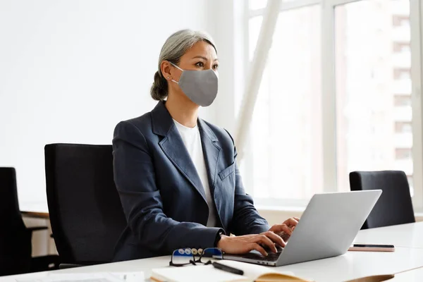 Empresária Cabelos Brancos Focada Máscara Facial Trabalhando Com Laptop Escritório — Fotografia de Stock