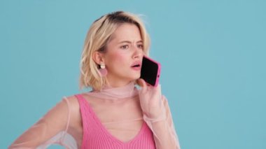 Mavi stüdyoda hoşnutsuz bir kadının telefonla konuşmasının yakın plan görüntüsü.