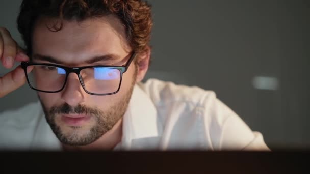 Ein Fröhlicher Mann Mit Brille Blickt Nachts Auf Den Laptop — Stockvideo