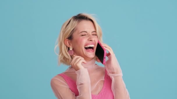 青いスタジオで電話で話している女性を笑っているのクローズアップビュー — ストック動画
