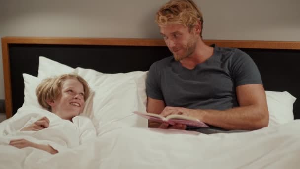 Lachende Vader Die Een Verhaal Voorleest Aan Zijn Zoon Bed — Stockvideo