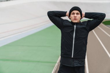 Stadyumda koşmadan önce kendine güvenen genç adam ısınıyor.