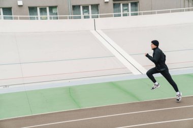 Stadyumda koşan kendinden emin genç bir sporcu.