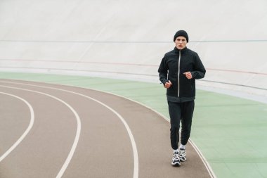 Stadyumda spor yaparken koşan yakışıklı sporcu.