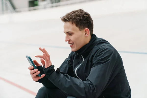 Desportista Jovem Atraente Usando Telefone Celular Enquanto Sentado Estádio Descansando — Fotografia de Stock