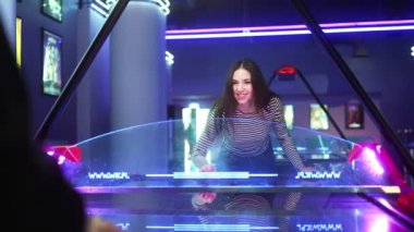 Oyun salonunda erkek arkadaşıyla masa hokeyi oynayan güzel bir kadın. Hüzünlü duygularını göster çünkü oyunu kaybet.