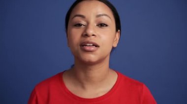 Gülümseyen İspanyol kadın kameraya mavi stüdyodaki ayna gibi bakıyor.